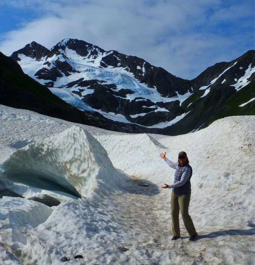Tami is standing on the last remaining snowfield caused by an avalanche next to the Byron Glacier.