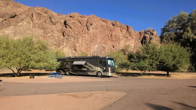 Our RV parked next to a massive rock wall at River Island State Park in Arizona.