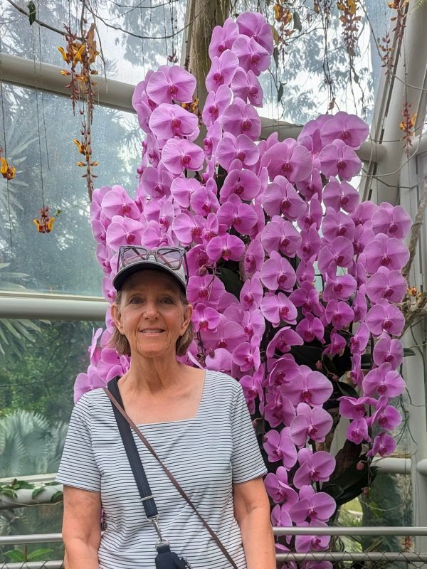 Tami standing in front of a massive blooming orchid at the Singapore Botanical Garden.